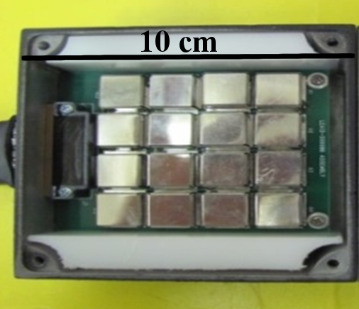 Photograph of one detector head: a printed circuit board holding a 4-by-4 grid of 16 metallic square boron-10-filled silicon-pillar detectors, mounted in an aluminum frame, with a 10 centimeter scale bar across the top showing the head is roughly hand-sized and under 1 cm thick.